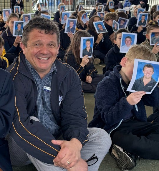 Photo of Brendan Constable the school principal with students holding up portraits of him on principals day