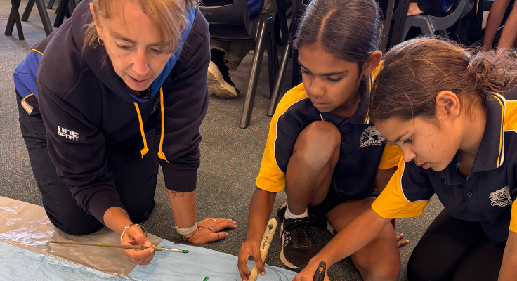 Photo of two students and an SLSO working on art in their classroom.