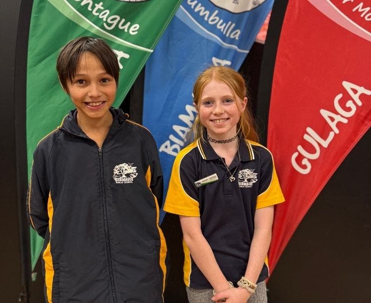 Photo of two students on stage, with our house banners in the background